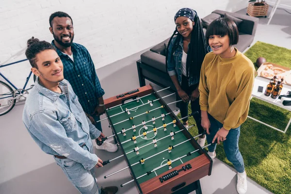 Vista de ángulo alto de amigos multiétnicos jugando al futbolín - foto de stock