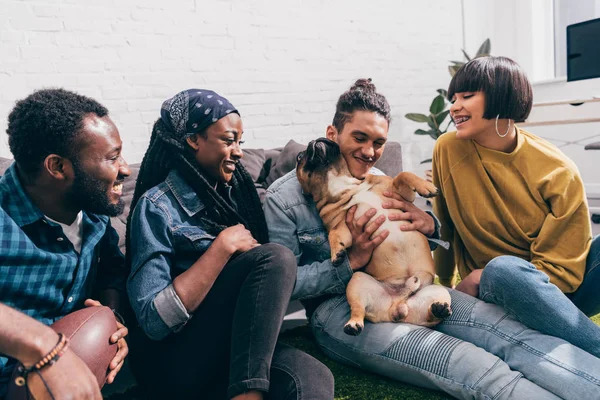 Group of smiling young multicultural friends with french bulldog — Stock Photo