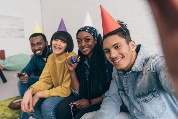 Young mixed race doing selfie with multiethnic friends in party hats — Stock Photo