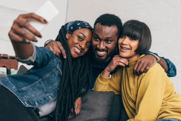 Sorrindo mulher negra tomando selfie com dois amigos multiétnicos — Fotografia de Stock