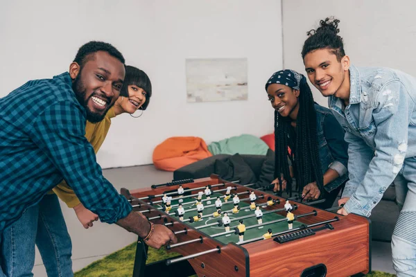 Sorridente gruppo di amici multiculturali che giocano a calcio balilla — Foto stock