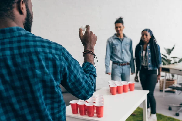 Cropped image of young african american man preparing to throw ball in beer pong game — Stock Photo
