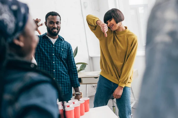 Amigos jogando cerveja pong e jovem mulher fazendo polegar para baixo — Fotografia de Stock