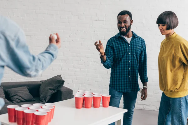 Cropped image of multiethnic group of friends playing beer pong at table — Stock Photo