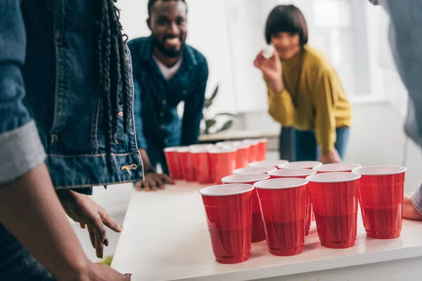 Tiro recortado de grupo multicultural de amigos jogando cerveja pong à mesa — Fotografia de Stock