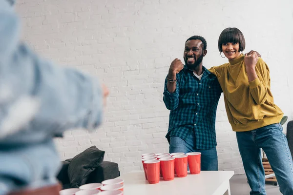 Deux jeunes amis multiculturels faisant geste gagnant à table avec bière pong — Photo de stock