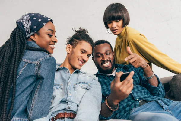 Jovem homem negro apontando para a tela do smartphone para amigos sorridentes — Fotografia de Stock