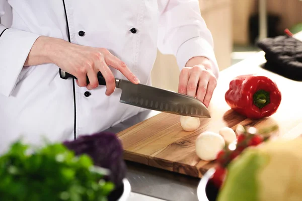 Close-up view of female chef cutting mushrooms on wooden board — Stock Photo