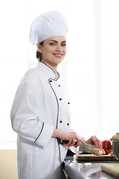 Profissional chef feminino corte pimenta na mesa da cozinha — Fotografia de Stock