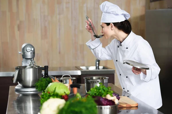 Female chef tasting dish on restaurant kitchen — Stock Photo