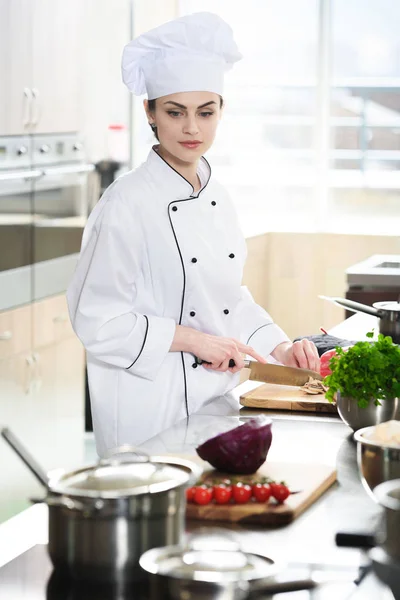 Profi-Köchin in Uniform schneidet Zutaten auf Küchentisch — Stockfoto