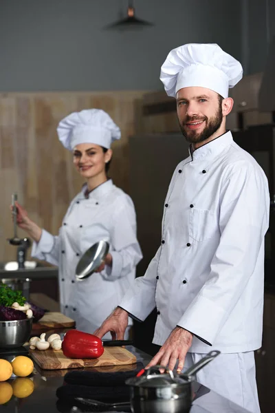 Chefs profesionales cocina de hombre y mujer en la cocina del restaurante - foto de stock