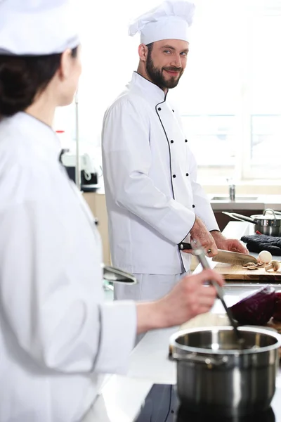 Професійний чоловік готує, дивлячись на свою колегу по кухні — стокове фото