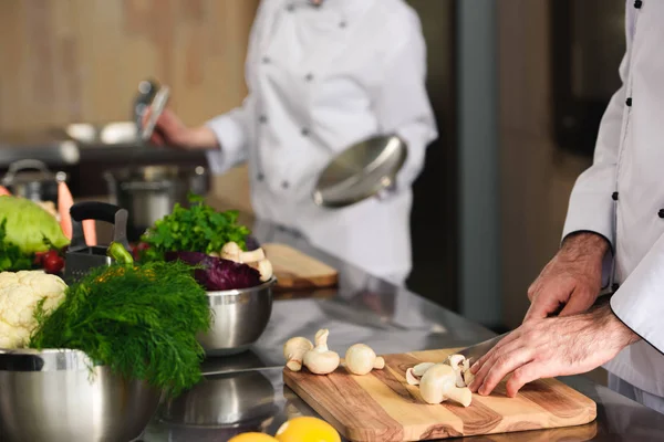 Vista de cerca del equipo profesional de cocineros preparando ingredientes en la cocina - foto de stock