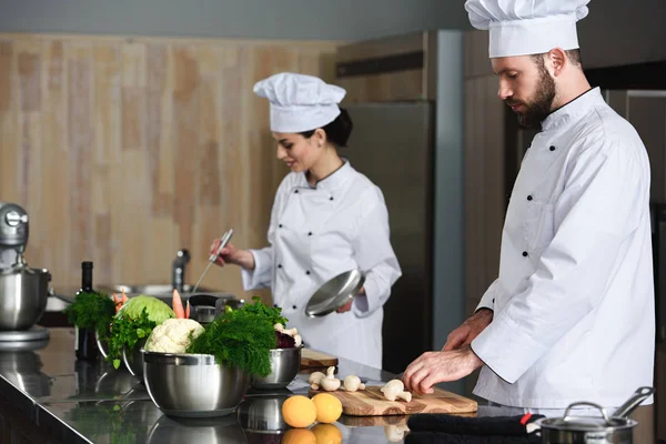 Chefs profissionais cozinhando ocupado por mesa de cozinha — Fotografia de Stock