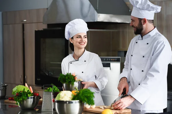 Chefs profesionales discutiendo receta y cocina en la cocina - foto de stock