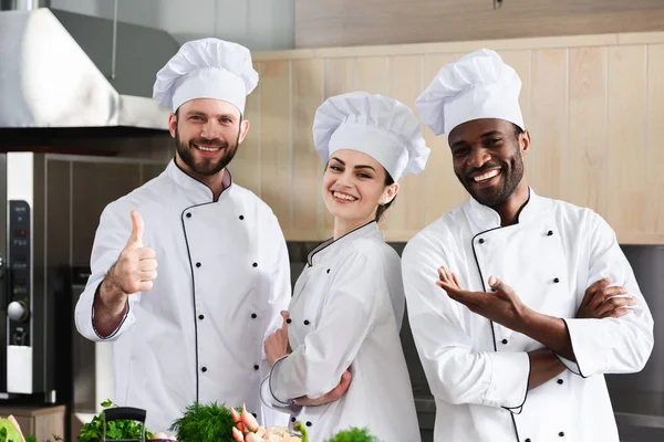 Homme cuisinier montrant pouce par son équipe multiraciale — Photo de stock