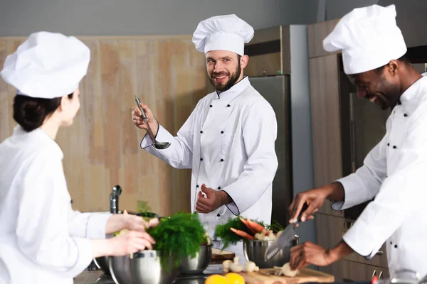 Equipe de chefs multirraciais cozinhar juntos por balcão de cozinha — Fotografia de Stock