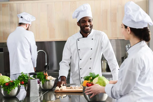 Cocineros multiculturales trabajando juntos por mostrador de cocina - foto de stock