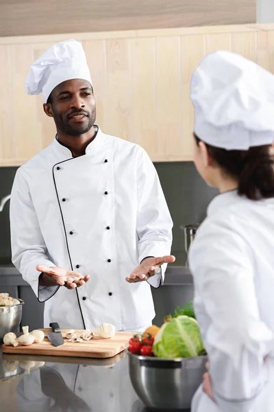 Multiracial chefs team discussing recipe and cooking on kitchen — Stock Photo