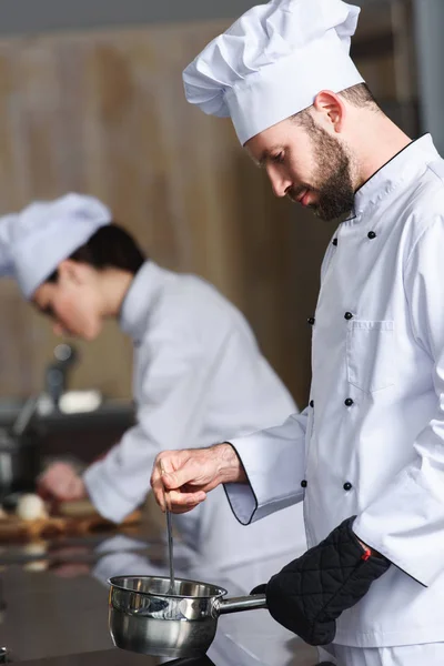 Homme cuisinier travaillant par son collègue féminin sur la cuisine moderne — Photo de stock