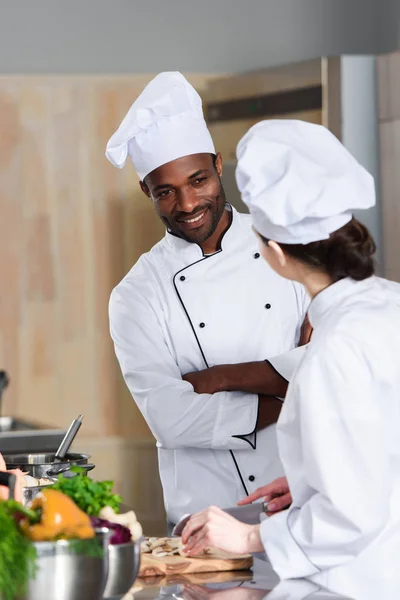 Équipe multiraciale de cuisiniers parlant tout en cuisinant sur la cuisine moderne — Photo de stock