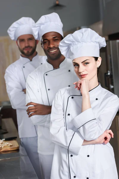 Équipe multiraciale de cuisiniers en uniforme blanc dans la cuisine du restaurant — Photo de stock