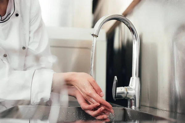 Vista recortada de cocinera lavándose las manos sobre fregadero de cocina - foto de stock