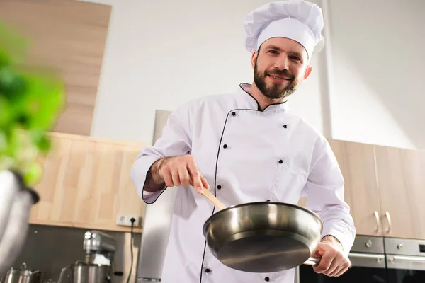 Мужчина шеф-повар держит сковородку на современной кухне — стоковое фото