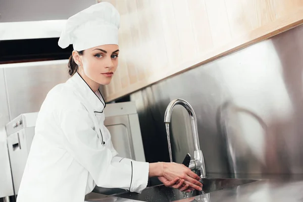 Chef donna lavarsi le mani sopra lavello della cucina — Foto stock