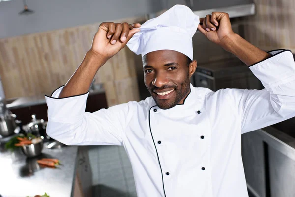 Chef afroamericano poniendo toque blanco en su cabeza - foto de stock