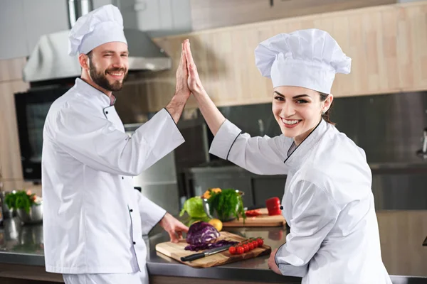 Professional chefs giving high five on modern kitchen — Stock Photo