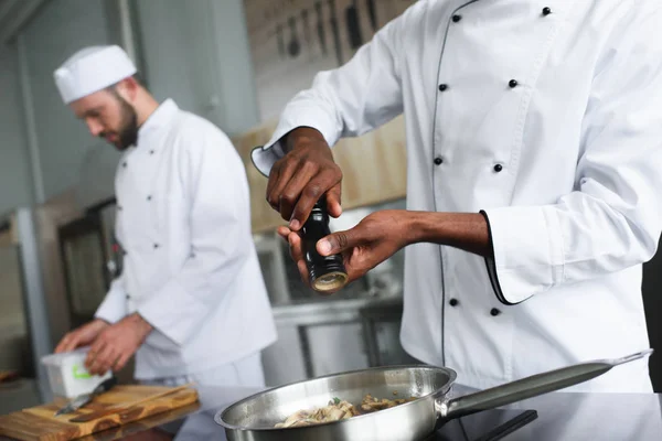 Cozinha equipe de chefs multirraciais e tempero prato quente — Fotografia de Stock