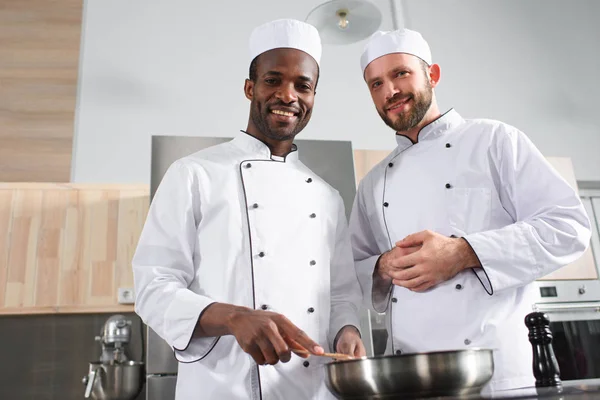 Multiracial team of male cooks working together by stove — Stock Photo