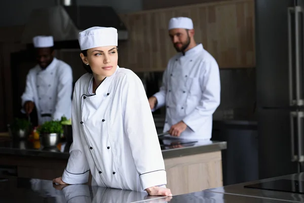 Hermoso chef mirando hacia fuera en la cocina del restaurante - foto de stock