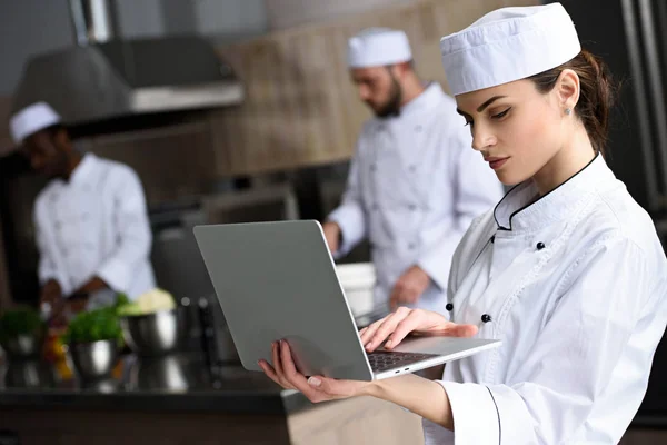 Beautiful chef using laptop at restaurant kitchen — Stock Photo