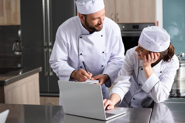 Köche nutzen Laptop in Restaurantküche und suchen Rezept — Stockfoto