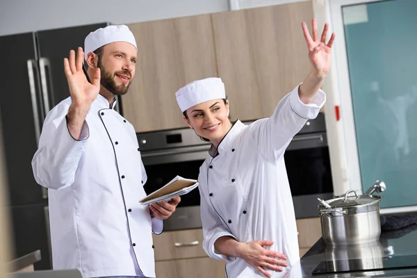 Chefs waving hands at restaurant kitchen — Stock Photo
