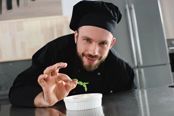 Beau chef ajoutant des herbes au plat à la cuisine du restaurant — Photo de stock