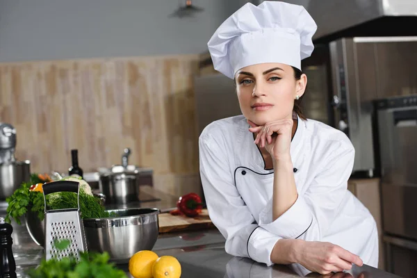 Attractive pensive chef looking at camera at restaurant kitchen — Stock Photo