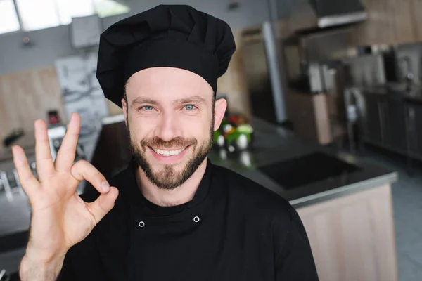 Sonriente guapo chef mostrando ok gesto en restaurante cocina - foto de stock