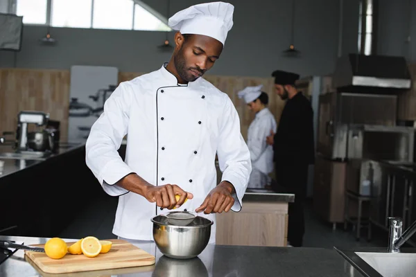 Chef americano africano espremendo limões na cozinha do restaurante — Fotografia de Stock