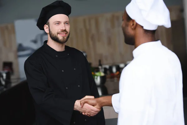 Multicultural chefs shaking hands at restaurant kitchen — Stock Photo