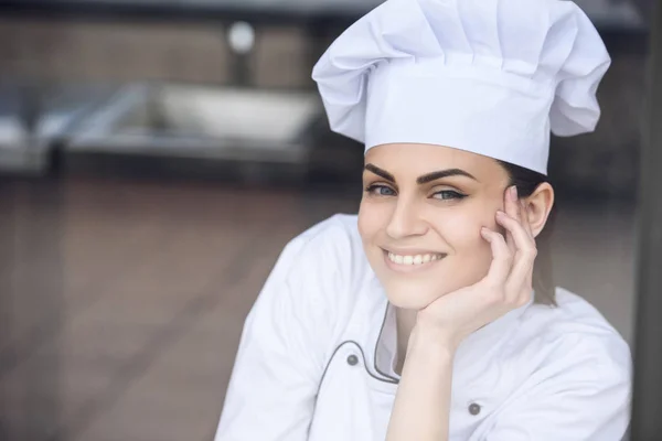 Smiling attractive chef looking at camera at restaurant kitchen — Stock Photo