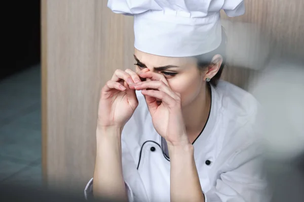 Chef llorando y sentado en el suelo en la cocina del restaurante - foto de stock