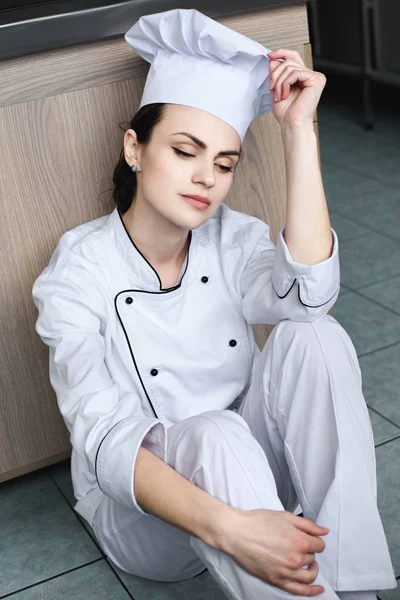 Привабливий шеф-кухар сидить на підлозі на кухні ресторану — стокове фото