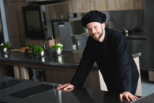 Guapo chef mirando la cámara en la cocina del restaurante - foto de stock