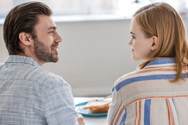 Young couple sitting at table and looking at each other during breakfast time — Stock Photo