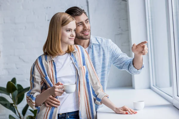 Mann zeigt mit Finger auf Freundin mit Kaffeetasse — Stockfoto