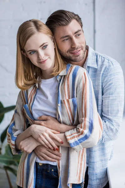 Young man hugging attractive stylish girlfriend from behind — Stock Photo